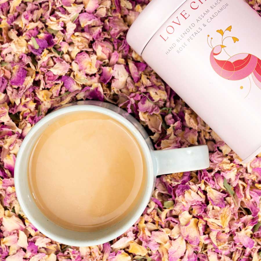 A cup of Love Chai and cointainer surrounded by petals | CHAI.COM