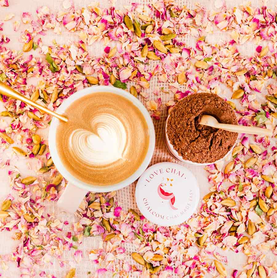 A cup of Love Chai and an open Love Chai container surrounded by petals | CHAI.COM
